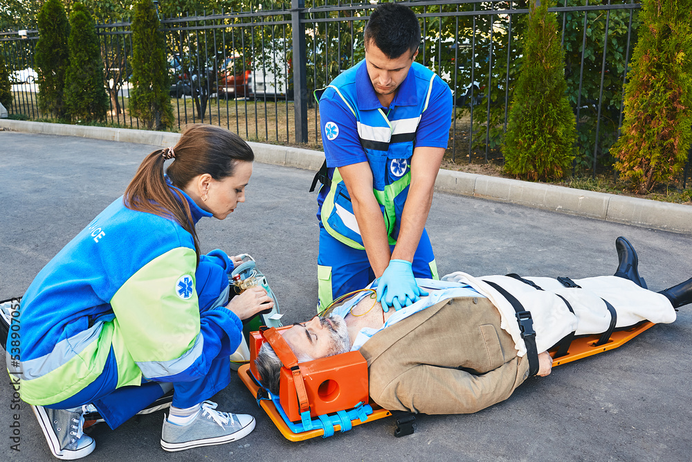Fototapeta premium Personnel of emergency service provide first aid to victim with medical equipment, give heart massage and CPR to patient to save his life. First aid, ambulance