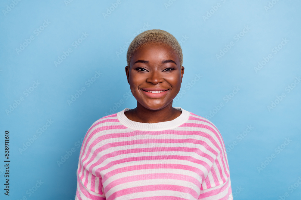 Photo of pleased optimistic girlfriend wears striped sweater toothy smile isolated on blue background Photo of pleased optimistic girlfriend wears striped sweater toothy smile isolated on blue background