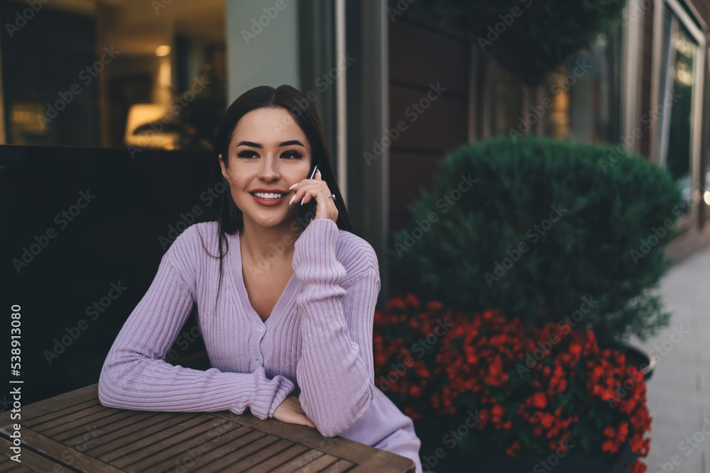 Fototapeta premium Smiling woman talking on smartphone in cafe