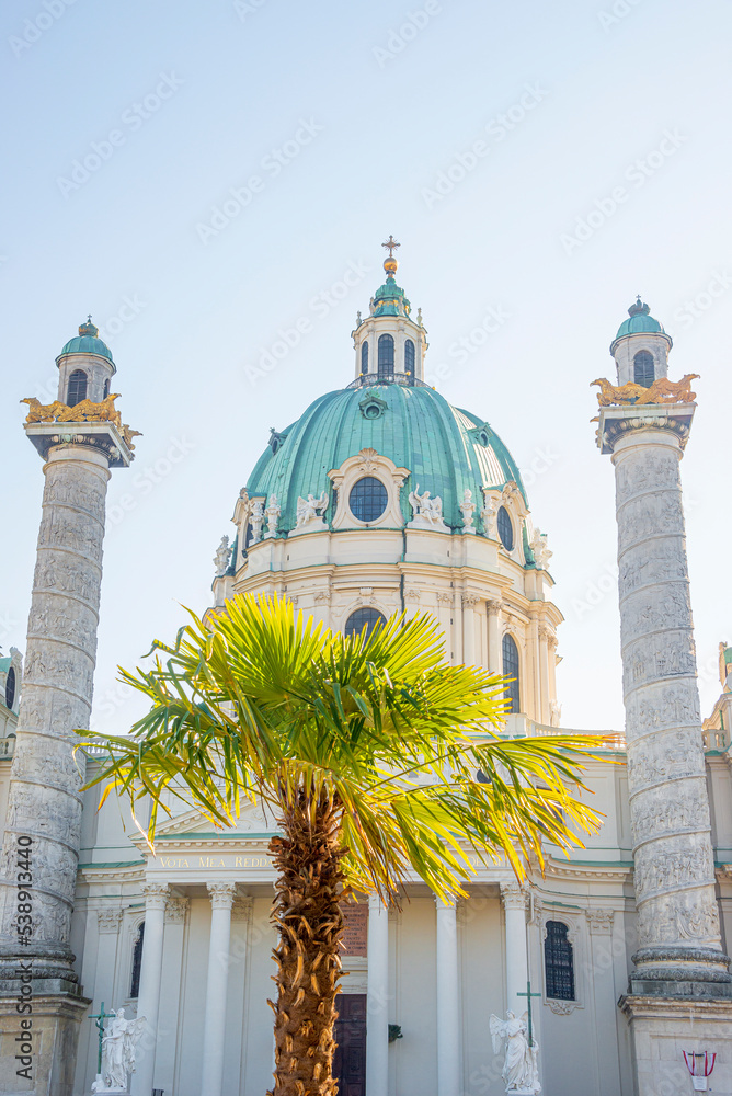 Front view of Saint Karl Cathedral in Vienna and palm tree at Autumn colors, Austria, at direct front sunlight of sunny day