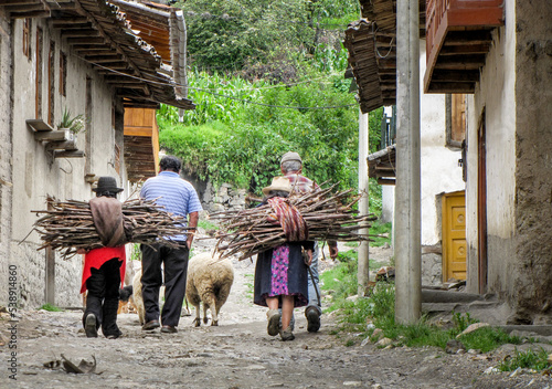 Typical scene of a small village in the Peruvian Andes with women carrying firewood, men walking in the street and sheep
