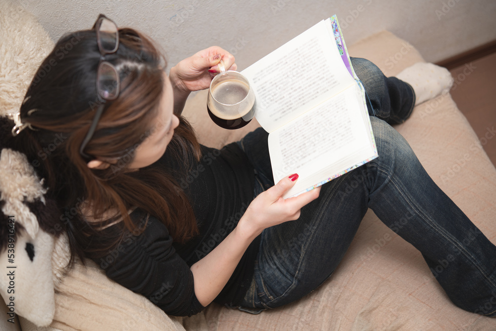 Obraz premium コーヒーを飲みながら本を読む女性