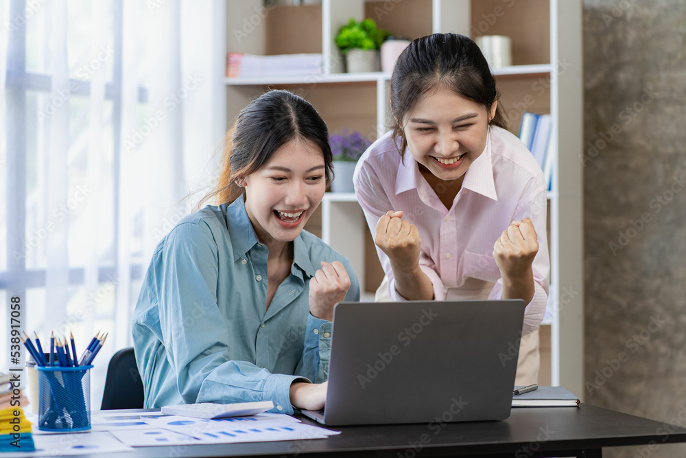 Two young Asian women discuss the concept of a new start-up project. analysis of financial planning and statistics and investment market on laptop computers Two young Asian women discuss the concept of a new start-up project. analysis of financial planning and statistics and investment market on laptop computers