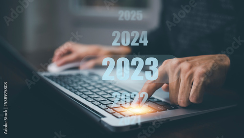 Businessman using laptop with new planning, Businessman using pen touch on 2023 year number, start new year concept digital trends, industry and business trend, strategy, investment,