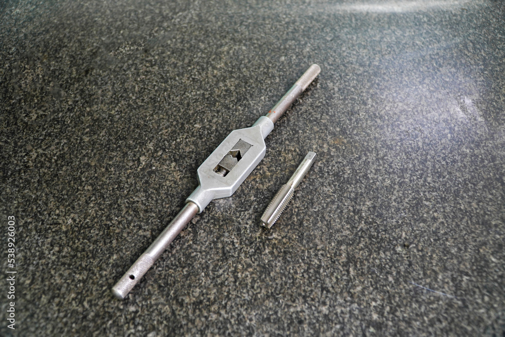 tap wrench on the black gray terrazzo table,Cut Threads and Drill and Tap Threads in Metal tap wrench on the black gray terrazzo table,Cut Threads and Drill and Tap Threads in Metal