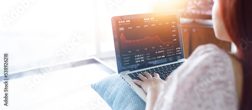 Woman using laptop with planning and strategy, Stock market, Business growth down, Concept of financial crisis, echnical price graph and indicator, red candlestick chart with analyzing forex trading. photo