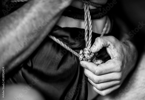 A young, slim, naked hot woman with decorative knots of natural ropes. Ancient Japanese art of aesthetic bondage and tying shibari kinbaku. Concept of BDSM sex games.