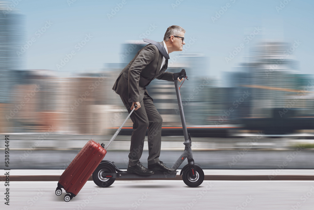 Businessman with luggage riding an electric scooter Businessman with luggage riding an electric scooter