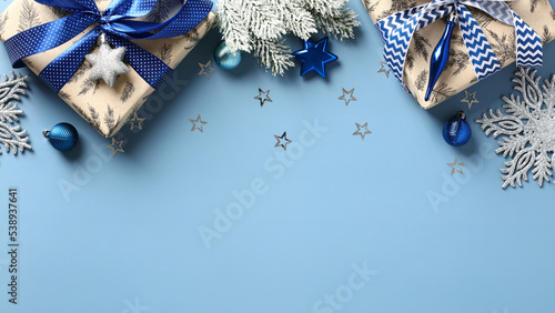 Fototapeta Naklejka Na Ścianę i Meble -  Stylish Christmas background with gift boxes, Xmas decorations, snowy fir branches, snowflakes on pastel blue table. Flat lay, top view. New Year greeting card design, banner template.
