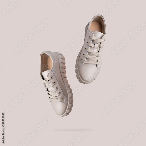 фотографія Beige gray leather female sneakers with lace isolated on beige background