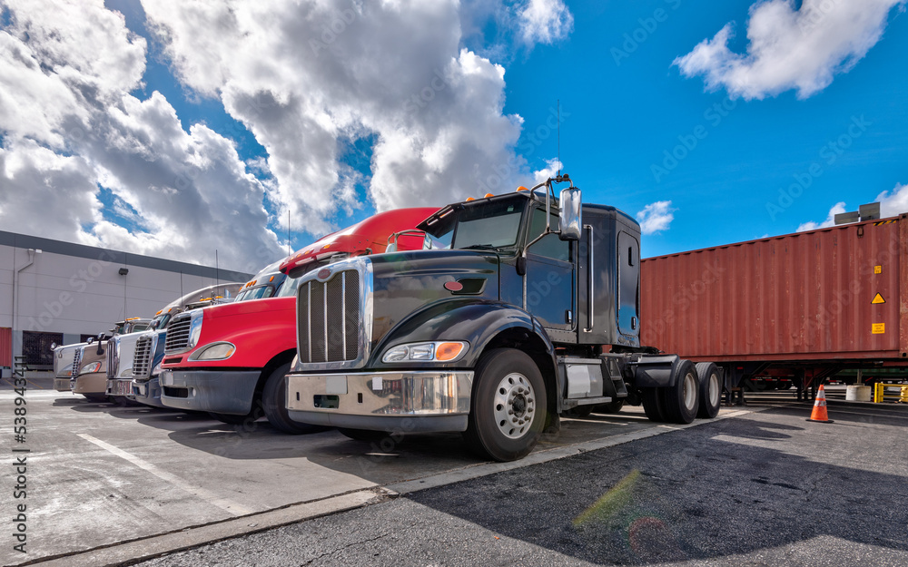 Lined up Semi truck heads on a parking lot at logistics warehouse.