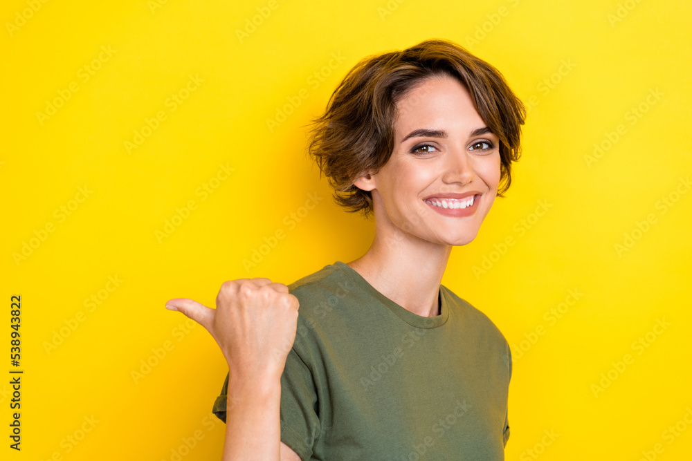 Portrait of gorgeous pretty woman with bob hairdo dressed khaki t-shirt directing empty space poster isolated on yellow color background Portrait of gorgeous pretty woman with bob hairdo dressed khaki t-shirt directing empty space poster isolated on yellow color background