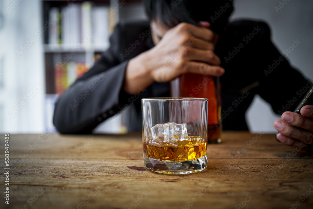 Glasses of whiskey in businessman's hands on wooden table background