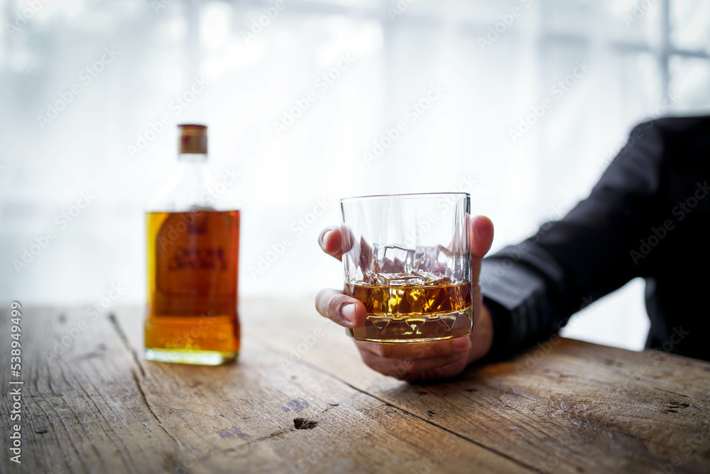 Glasses of whiskey in businessman's hands on wooden table background Glasses of whiskey in businessman's hands on wooden table background