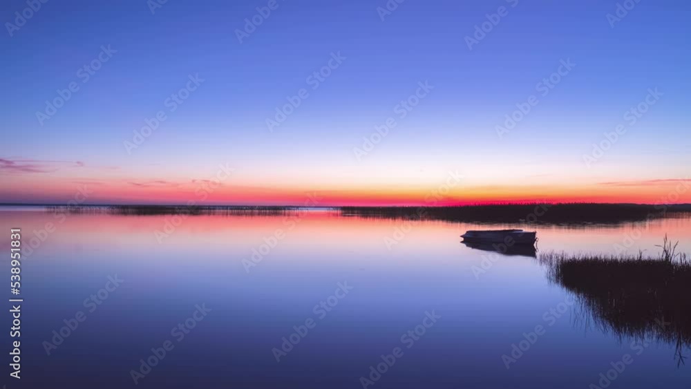 Beautiful sunrise on flat lake with boat. Timelapse, time is accelerated Beautiful sunrise on flat lake with boat. Timelapse, time is accelerated