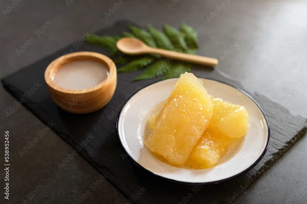 Sweet potato or Yam in syrup usually served coconut milk in vintage zinc coating dish on black stone background. Traditional desserts in Thailand.