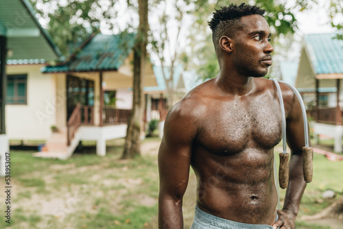 Black young sportsman resting while working out with jumping rope outdoors