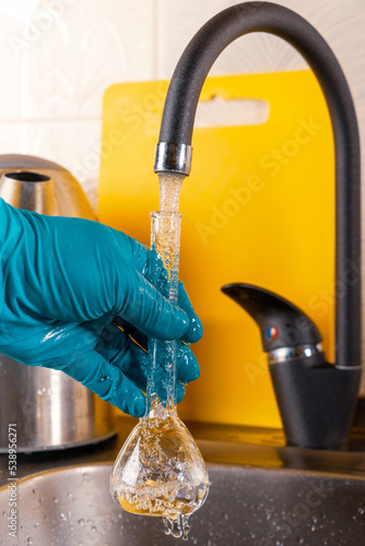 A specialist pours tap water into a glass flask.