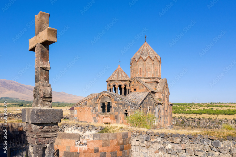 View of stone column with cross and Hovhannavank monastery on sunny summer day. Ohanavan, Armenia.