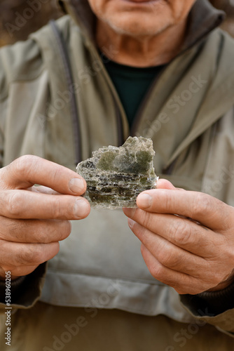 Natural unprocessed pieces of mica minerals in the hands of a man in a natural deposit.