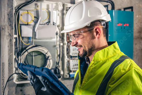 Canvas Print Man, an electrical technician working in a switchboard with fuses, uses a tablet