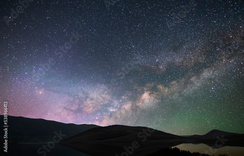 Beautiful night landscape. Mountains and small under bright milky way galaxy. Starry night.