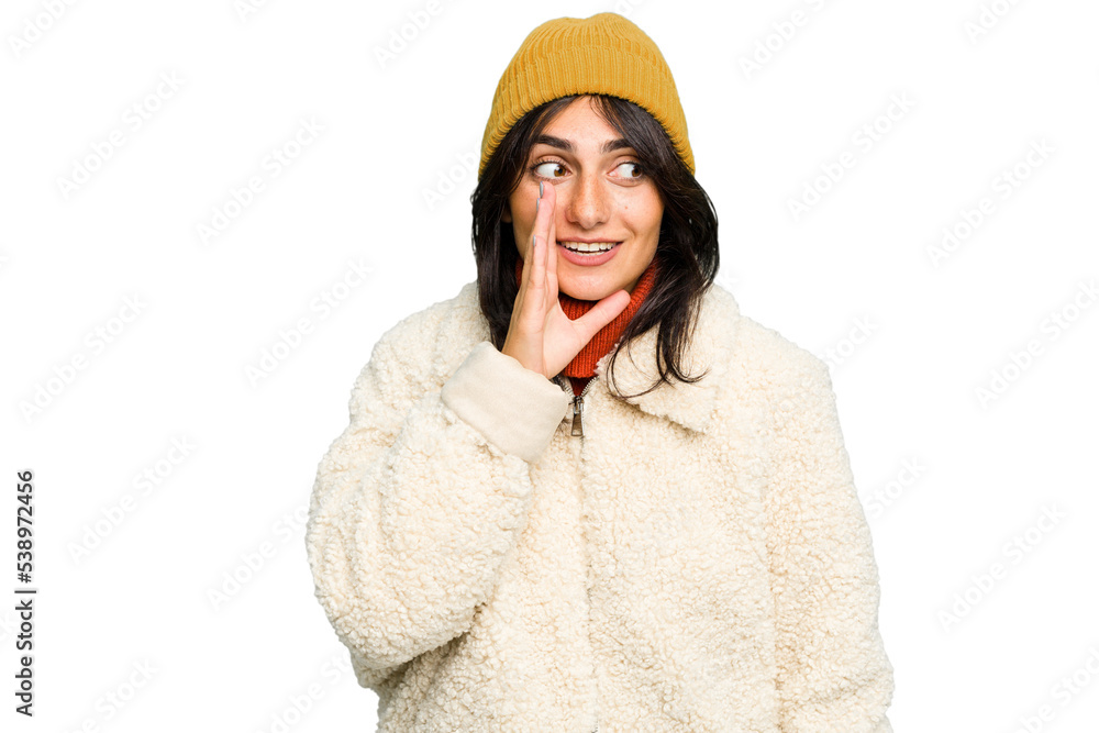 Young Indian woman wearing winter jacket and a wool cap isolated is saying a secret hot braking news and looking aside Young Indian woman wearing winter jacket and a wool cap isolated is saying a secret hot braking news and looking aside