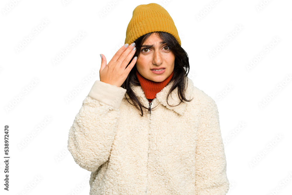 Young Indian woman wearing winter jacket and a wool cap isolated showing a disappointment gesture with forefinger. Young Indian woman wearing winter jacket and a wool cap isolated showing a disappointment gesture with forefinger.