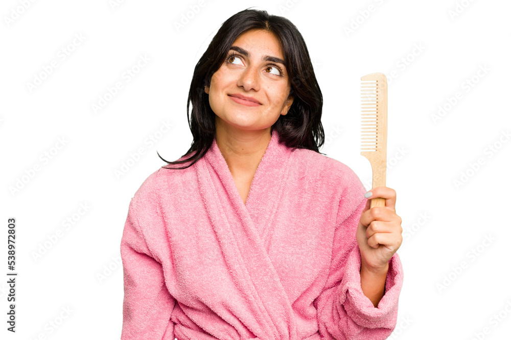 Young woman in a bathrobe holding an hair comb isolated dreaming of achieving goals and purposes Young woman in a bathrobe holding an hair comb isolated dreaming of achieving goals and purposes