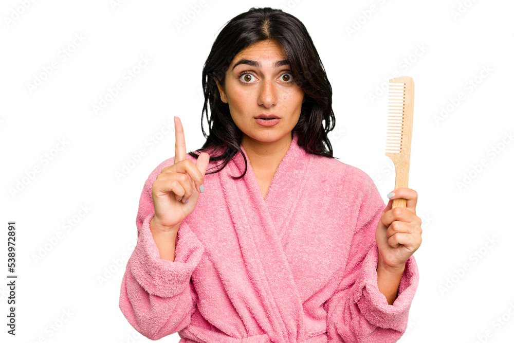 Young woman in a bathrobe holding an hair comb isolated having some great idea, concept of creativity. Young woman in a bathrobe holding an hair comb isolated having some great idea, concept of creativity.