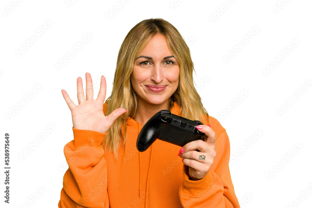 Young caucasian gamer woman holding a game controller isolated on green chroma background smiling cheerful showing number five with fingers. Young caucasian gamer woman holding a game controller isolated on green chroma background smiling cheerful showing number five with fingers.