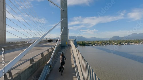 Woman Bike riding on a Bicycle Path over Golden Ears Bridge over the Fraser River. Pitt Meadows, Langley, Greater Vancouver, British Columbia, Canada. High quality 4k footage photo