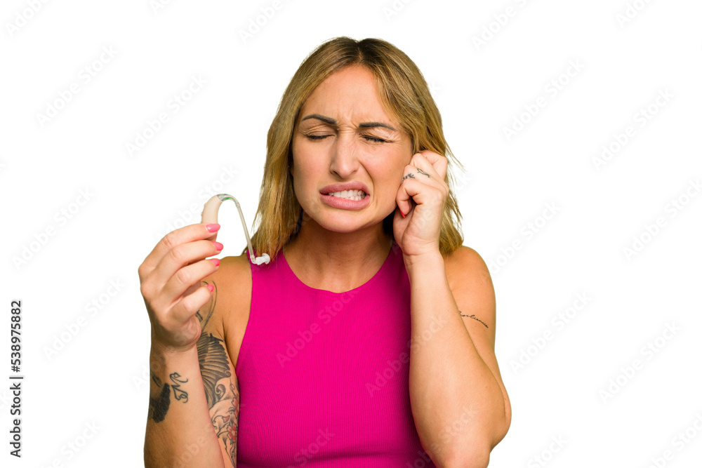 Young caucasian woman wearing hearing aid isolated on green chroma background covering ears with hands. Young caucasian woman wearing hearing aid isolated on green chroma background covering ears with hands.