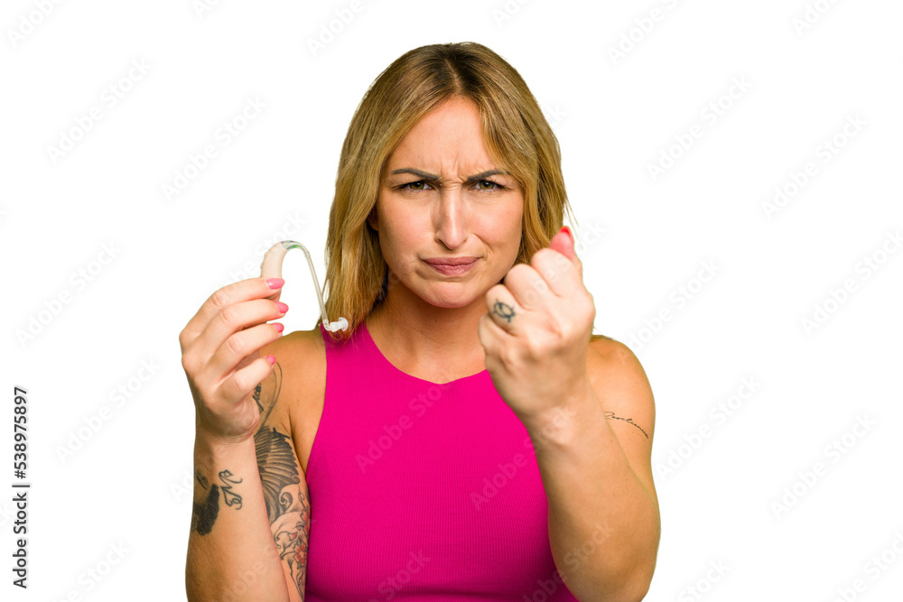 Young caucasian woman wearing hearing aid isolated on green chroma background showing fist to camera, aggressive facial expression. Young caucasian woman wearing hearing aid isolated on green chroma background showing fist to camera, aggressive facial expression.
