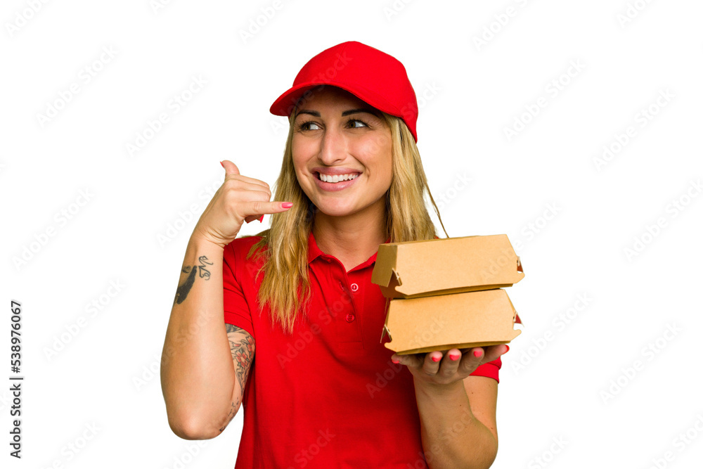 Young caucasian delivery woman holding a burger isolated on green chroma background showing a mobile phone call gesture with fingers. Young caucasian delivery woman holding a burger isolated on green chroma background showing a mobile phone call gesture with fingers.