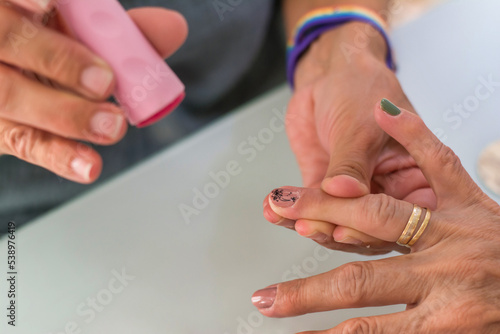 Close-up of an adult woman's hands doing nail impressions. Hands of a beautician giving a manicure to a client in her workspace in natural daylight. Beauty salon