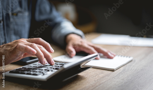 Businessman use a calculator to calculate checks Finance and accounting numbers on the desk.