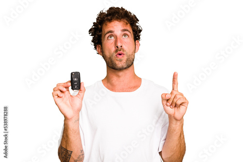 Young caucasian man holding car keys isolated pointing upside with opened mouth.