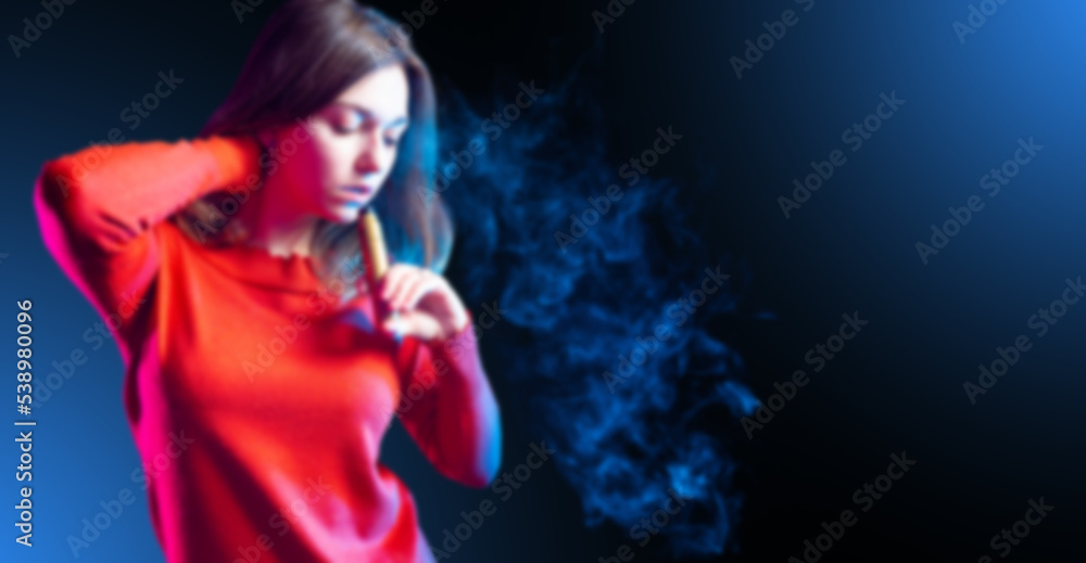 Woman smokes vape. Girl blows smoke from mouth. Female student uses electronic cigarette. Woman vaper straightens hair. Lady vaper on dark background. Vaping gadget in girls hand. Art blurred Woman smokes vape. Girl blows smoke from mouth. Female student uses electronic cigarette. Woman vaper straightens hair. Lady vaper on dark background. Vaping gadget in girls hand. Art blurred