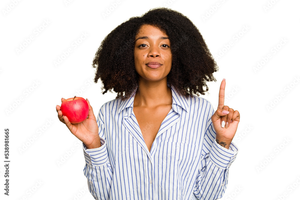 Young African American woman with a red apple isolated showing number one with finger. Young African American woman with a red apple isolated showing number one with finger.