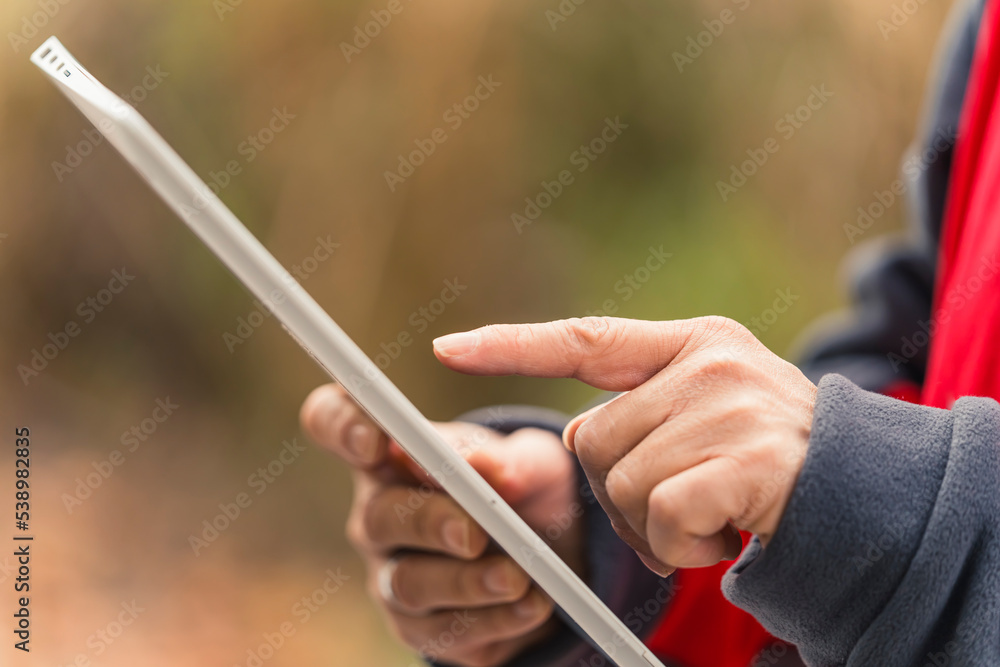 Close up of the hands of caucasian, middle-aged man, using an electronic tablet for work, checking information, swiping with one finger. High quality photo