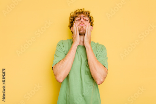 Young caucasian man isolated on yellow background whining and crying disconsolately. photo