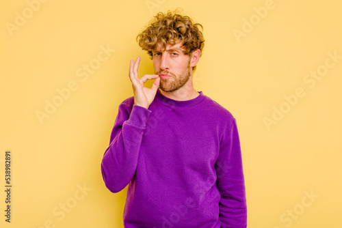 Konstfotografi Young caucasian man isolated on yellow background with fingers on lips keeping a secret