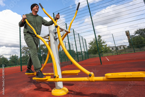 man trains on a trainer on a sports ground.