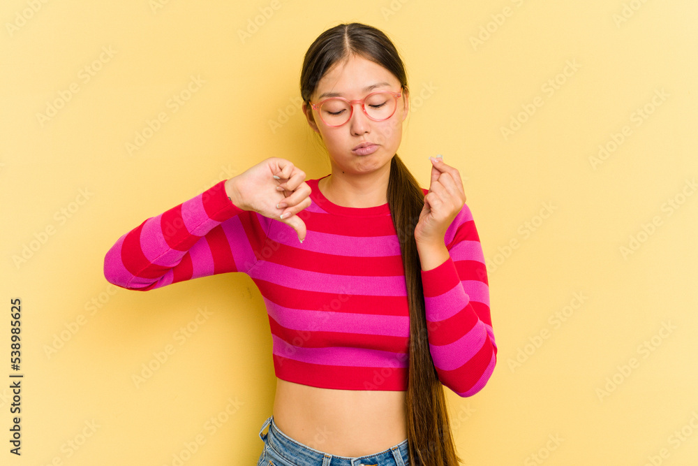 Young Asian woman isolated on yellow background showing that she has no money.