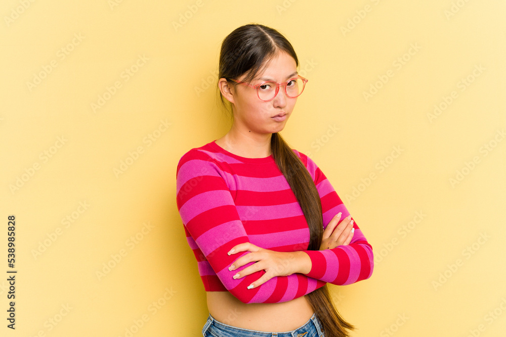 Young Asian woman isolated on yellow background suspicious, uncertain, examining you. Young Asian woman isolated on yellow background suspicious, uncertain, examining you.
