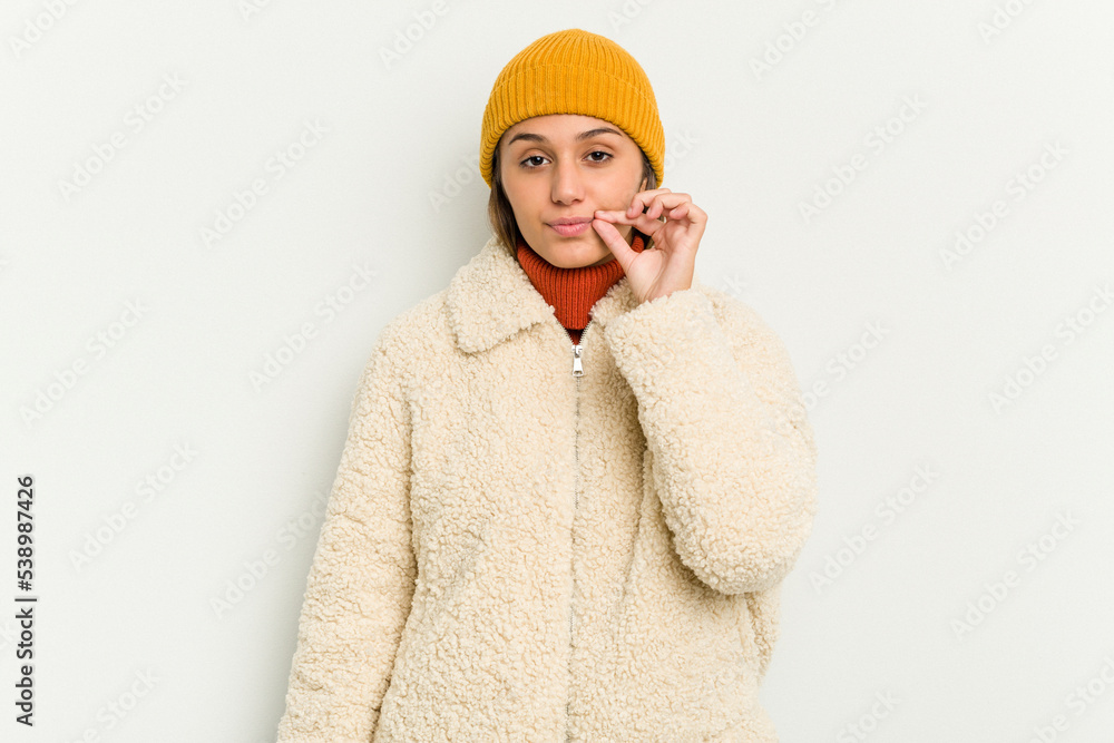 Young Indian woman wearing winter jacket isolated on white background with fingers on lips keeping a secret.