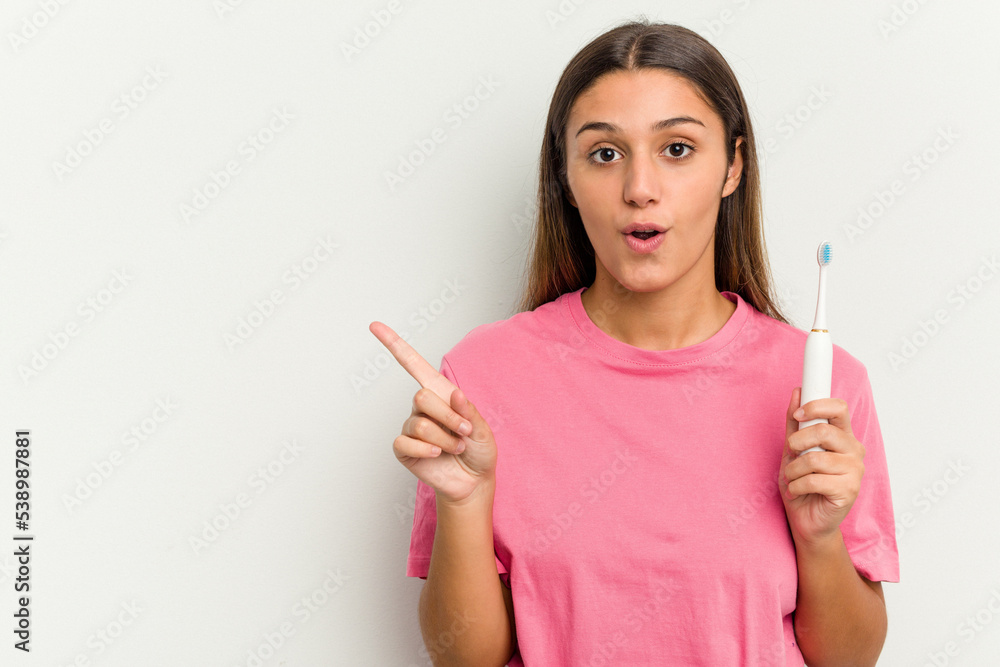 Young Indian woman brushing teeth isolated on white background pointing to the side Young Indian woman brushing teeth isolated on white background pointing to the side