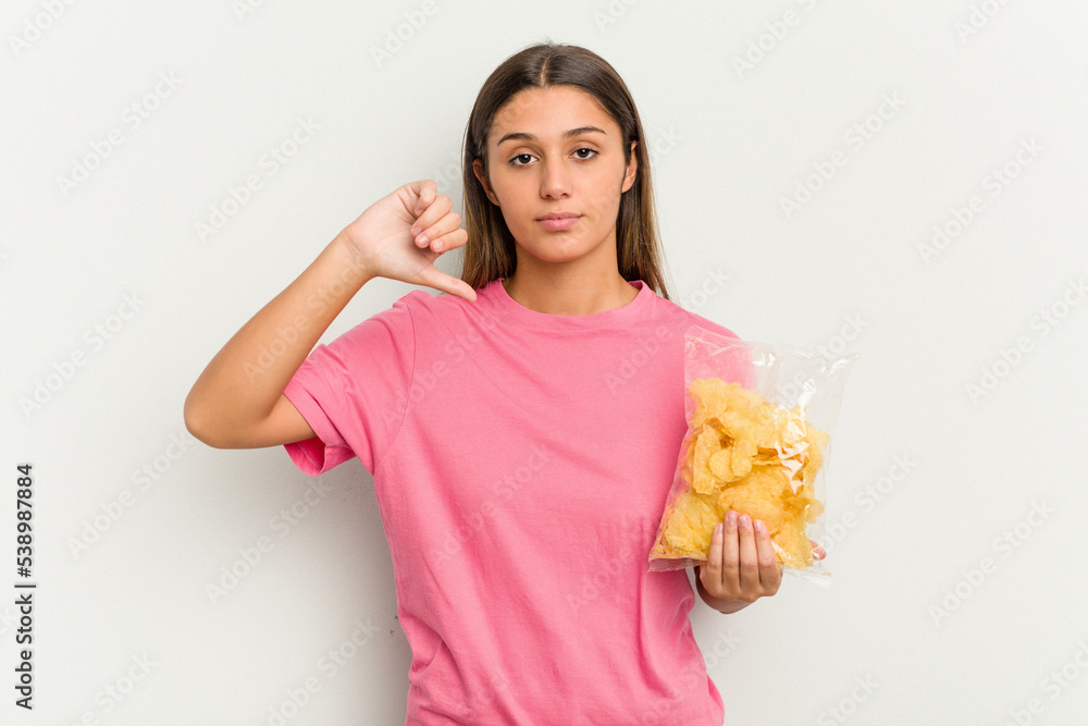 Young Indian woman holding crips isolated on white background showing a dislike gesture, thumbs down. Disagreement concept. Young Indian woman holding crips isolated on white background showing a dislike gesture, thumbs down. Disagreement concept.