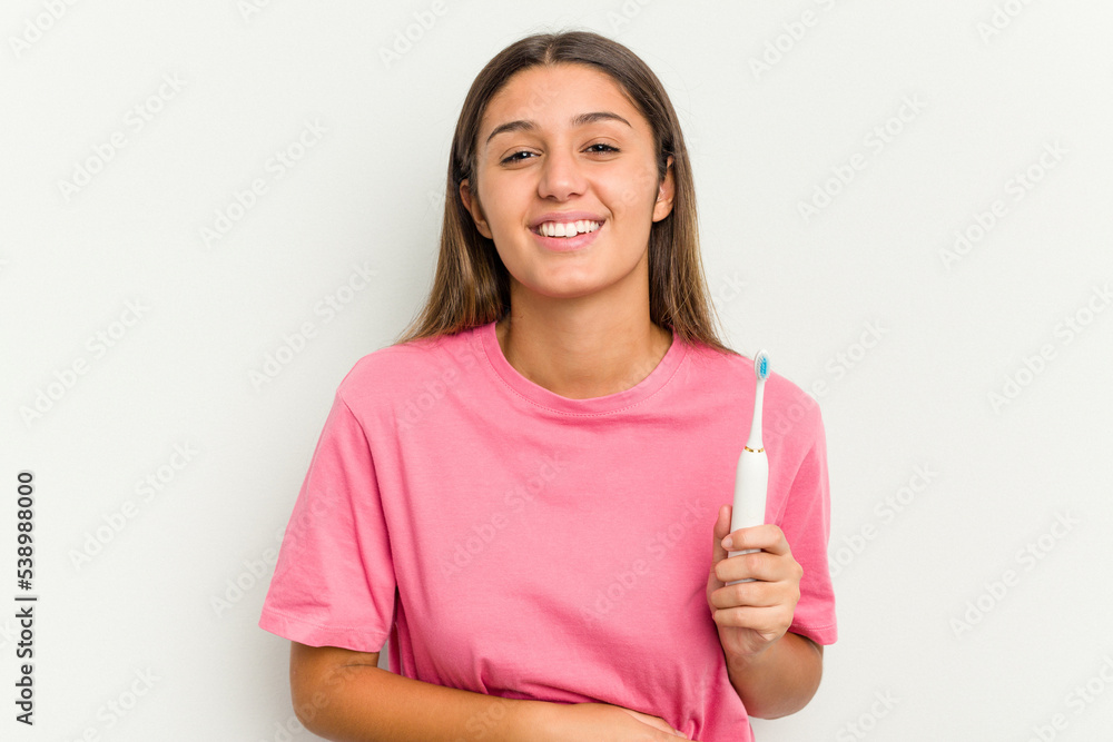Young Indian woman brushing teeth isolated on white background laughing and having fun. Young Indian woman brushing teeth isolated on white background laughing and having fun.